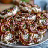Festive St. Patrick's Day Shamrock Pretzel Bites with creamy white chocolate and green sprinkles, arranged in clover shapes on a baking sheet.