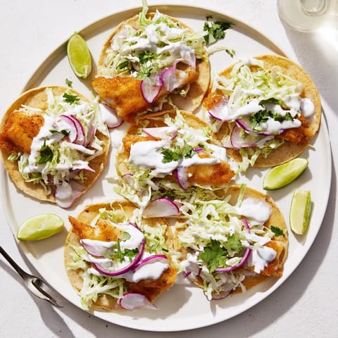 Freshly grilled fish fillets nestled in soft flour tortillas with shredded cabbage, cilantro, and creamy sauce, topped with lime for vibrant Fish Tacos.