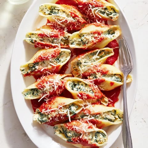 Jumbo pasta shells generously filled with ricotta and spinach, nestled in rich tomato sauce and served alongside garlic bread.