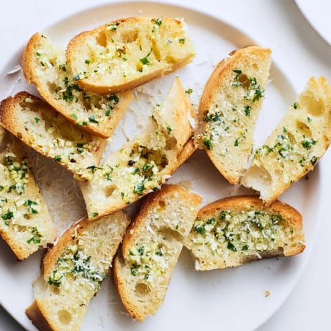 Freshly toasted Garlic Bread brushed with garlic-herb butter, served warm alongside a steaming bowl of tomato pasta.