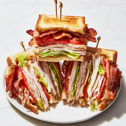 A toasted Turkey Club Sandwich is cut on the diagonal to show layers of juicy turkey and crunchy bacon.