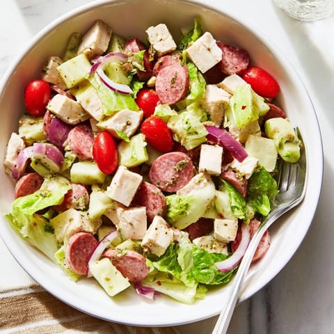 Freshly chopped Italian Deli Chopped Chicken Salad with juicy chicken, savory salami, and crisp provolone cheese over vibrant romaine lettuce.