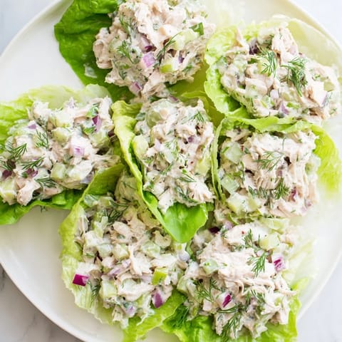 A close-up of Dill Pickle Chicken Salad Lettuce Cups, with creamy dressing coating shredded chicken and crunchy dill pickle bits.  