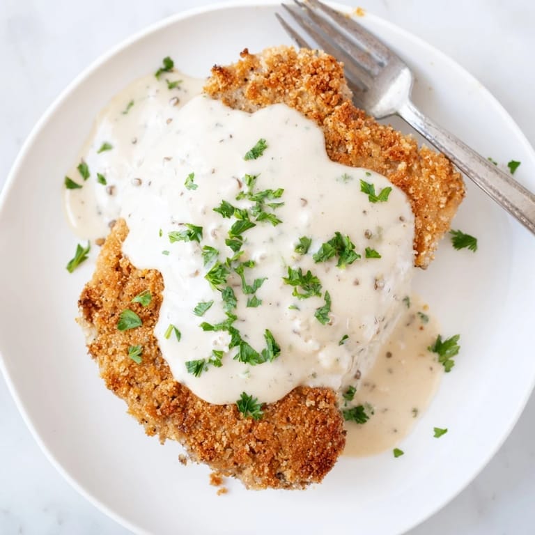 Fried cube steak with crunchy breading and rich gravy, ready to serve with a comforting side dish.