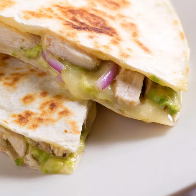 Freshly cooked Chicken Avocado Quesadilla with melted Monterey Jack, red onion slices, and avocado, ready to serve with a side of salsa.