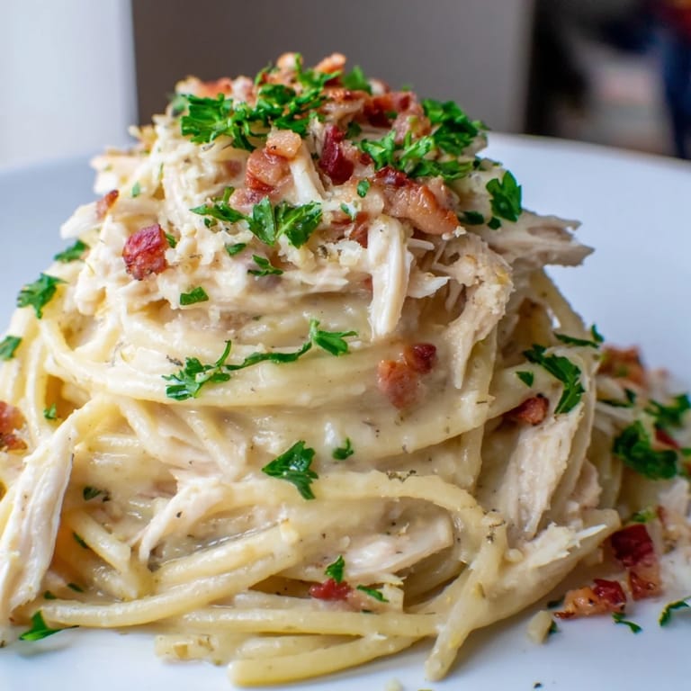 Glossy Chicken Carbonara pasta features Parmesan shavings and black pepper, ready to enjoy with a glass of wine.