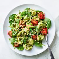 Bright cherry tomatoes and fresh spinach mingle with tender pesto-coated tortellini in a vibrant, chilled salad.  
