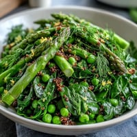 Vibrant Spring Green Bowl with blanched peas, asparagus, and spinach over fluffy quinoa, finished with lemon dressing and seeds.